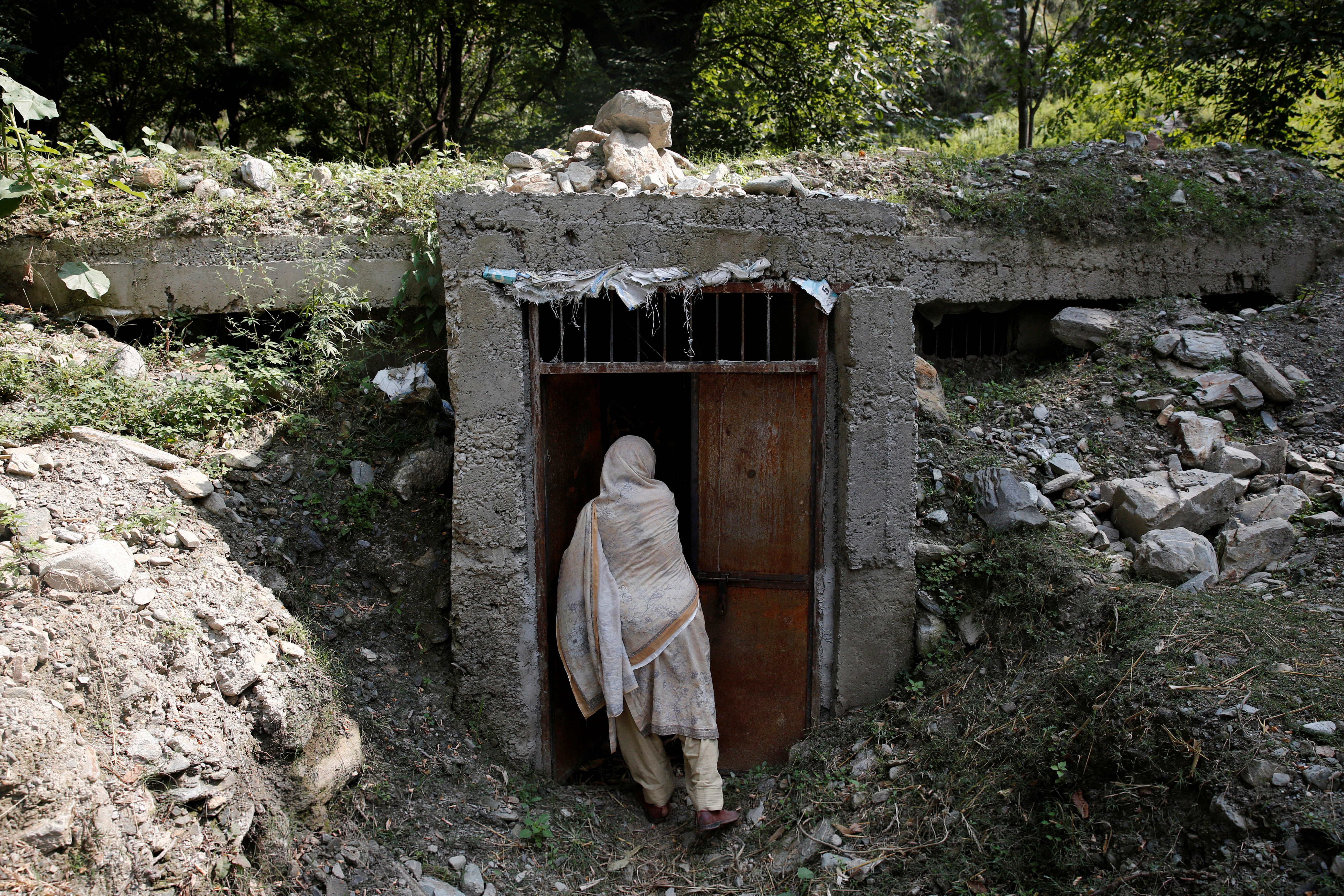 A woman opens the door of a bunker that the villagers said was built to take shelter in the wake of exchange of gun fire between Indian and Pakistani soldiers near the Line of Control between India and Pakistan in Teetwal